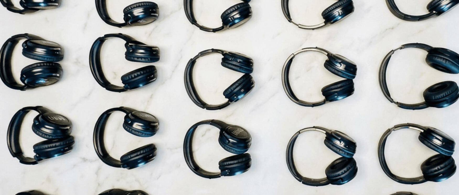 Birdseye image of Flow Silent Disco headphones laying in unison on white marble Birdseye image of Flow Silent Disco headphones laying in unison on white marble